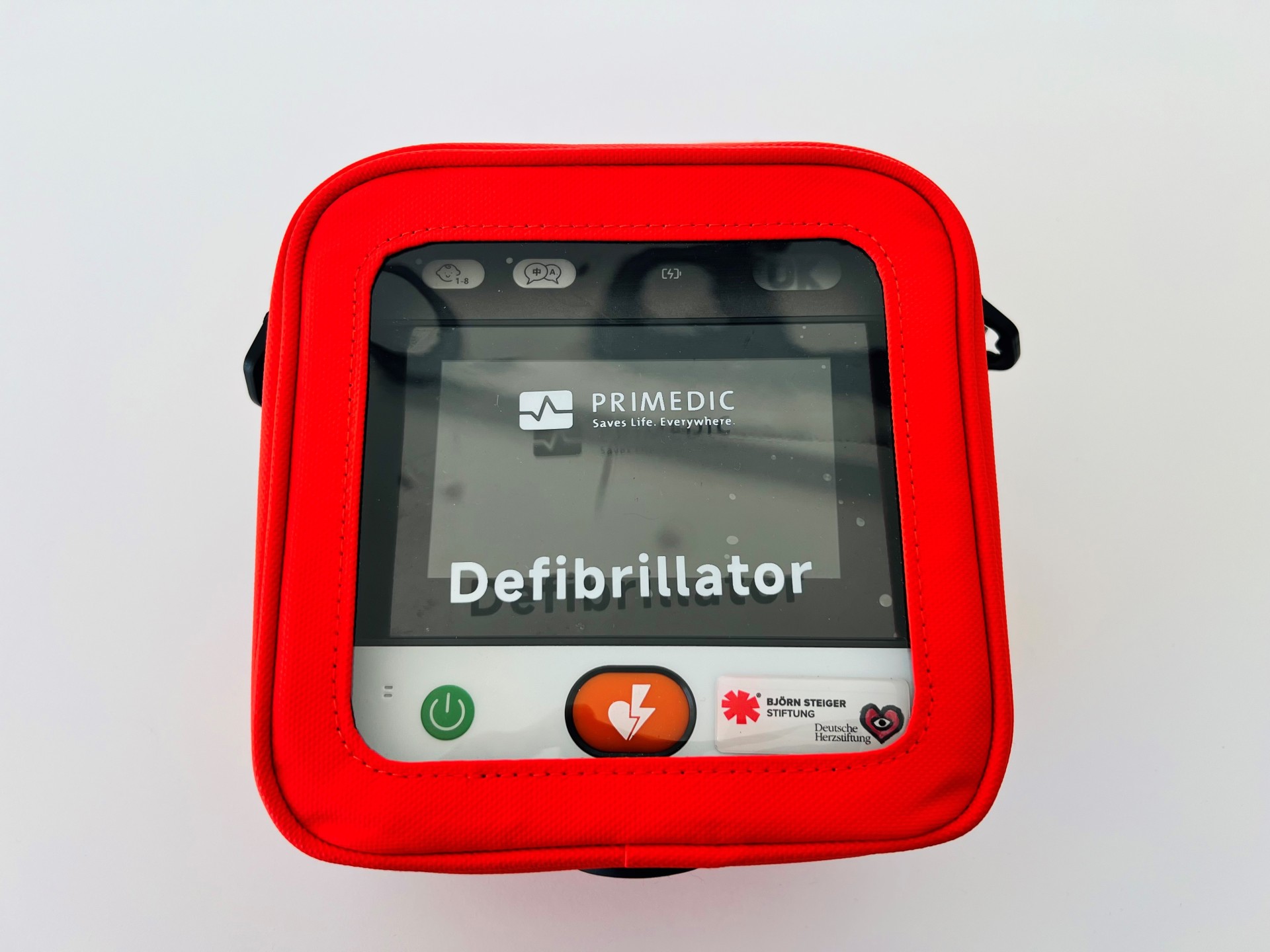 Eine rote, quadratische Tasche mit Sichtfenster zeigt einen Defibrillator von PRIMEDIC.