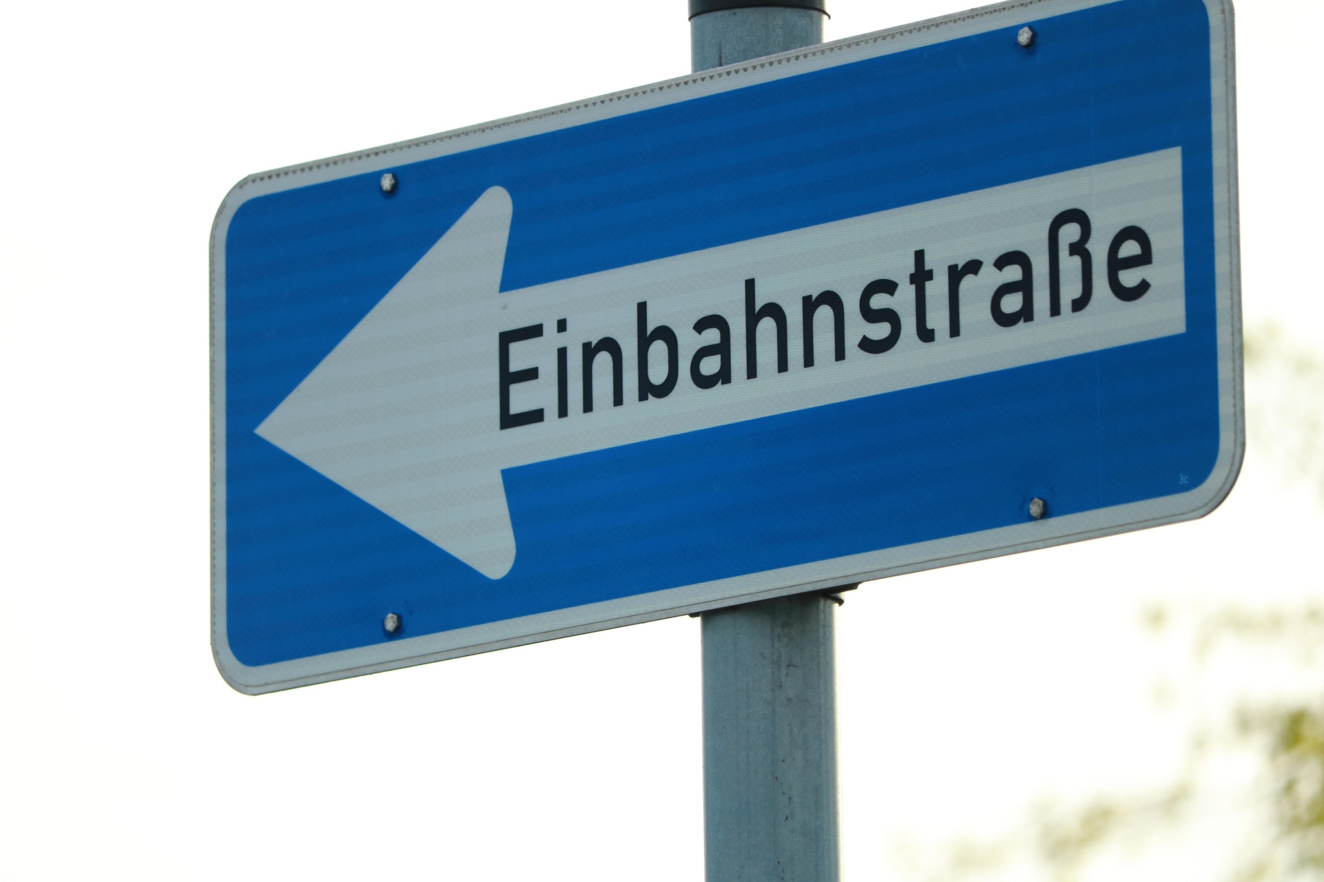 Es ist ein Straßenschild abgebildet blau mit weißem Pfeil nach links mit den Worten Einbahnstraße